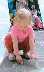 Маленькая девочка рисует на асфальте